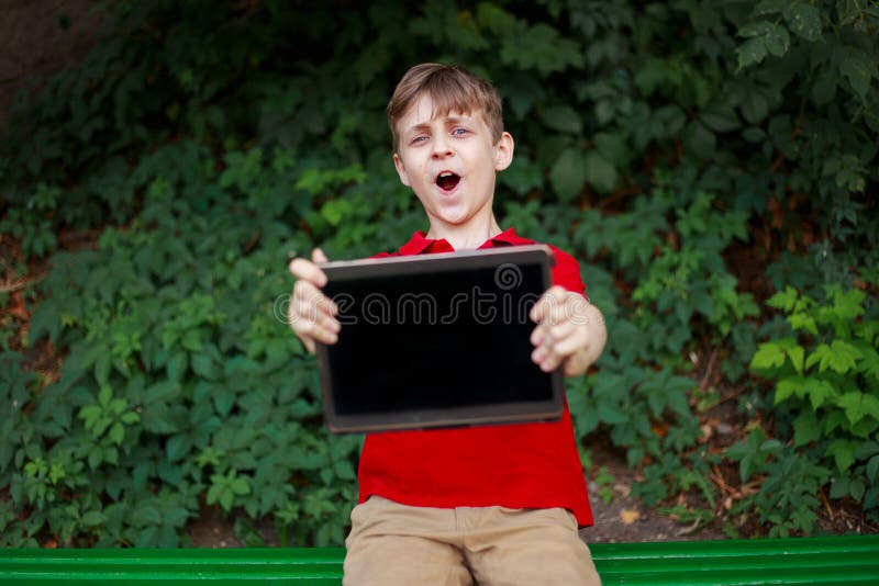 De gelukkige tablet van de jongensholding in handen Onderwijs, elektronisch spelenverslaving, kinderjaren, familie en mensenconce stock afbeelding De gelukkige tablet van de jongensholding in handen Onderwijs, elektronisch spelenverslaving, kinderjaren, familie en mensenconce stock afbeelding