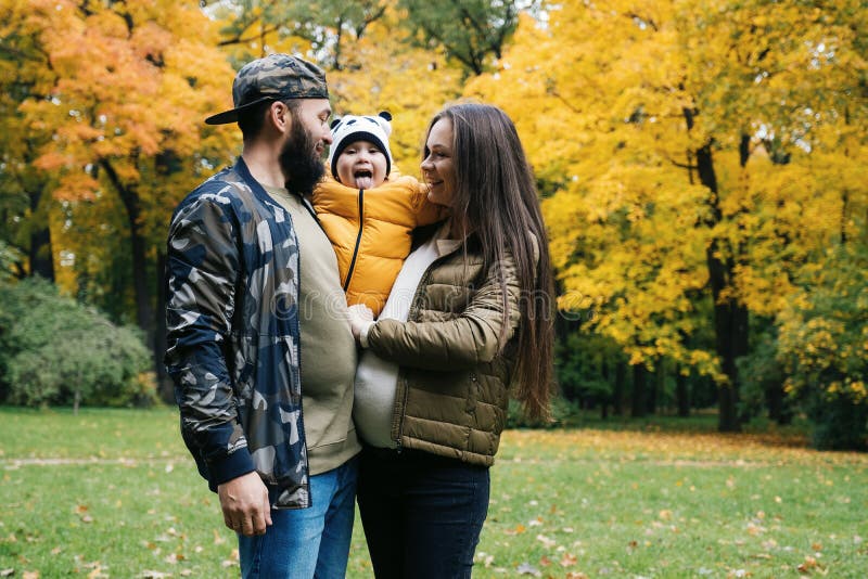 De de gelukkige vader en baby van de familiemoeder op de herfstgang in het park royalty-vrije stock afbeelding De de gelukkige vader en baby van de familiemoeder op de herfstgang in het park royalty-vrije stock afbeelding