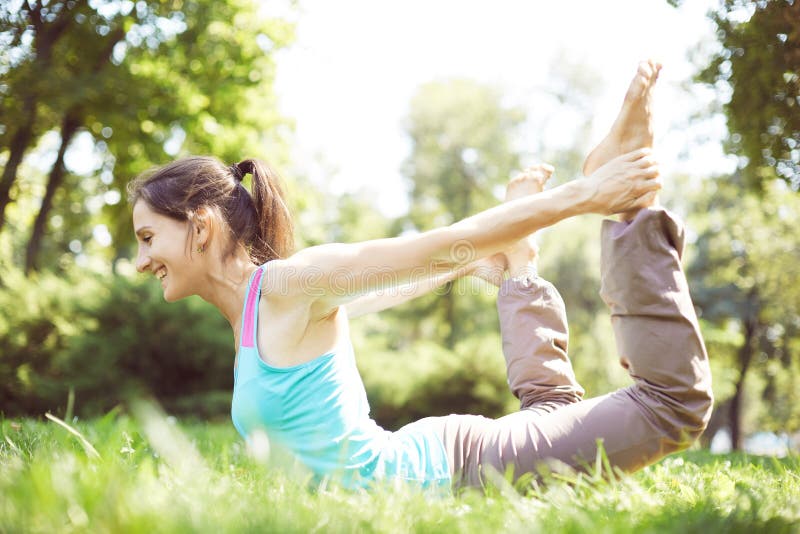 De gelukkige vrouw die yogaoefeningen doen, mediteert in het park stock fotografie De gelukkige vrouw die yogaoefeningen doen, mediteert in het park stock fotografie