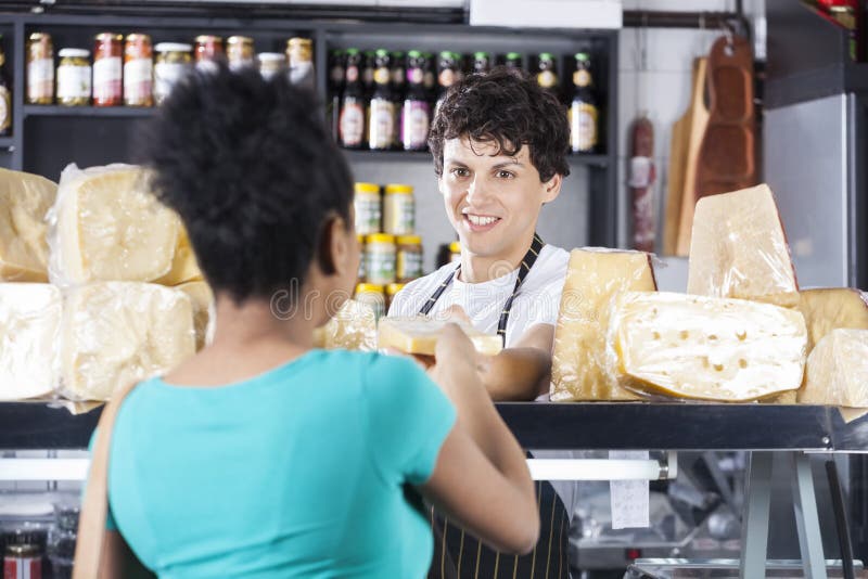 De gelukkige Vrouwelijke Klant van Verkopersselling cheese to stock afbeeldingen De gelukkige Vrouwelijke Klant van Verkopersselling cheese to stock afbeeldingen