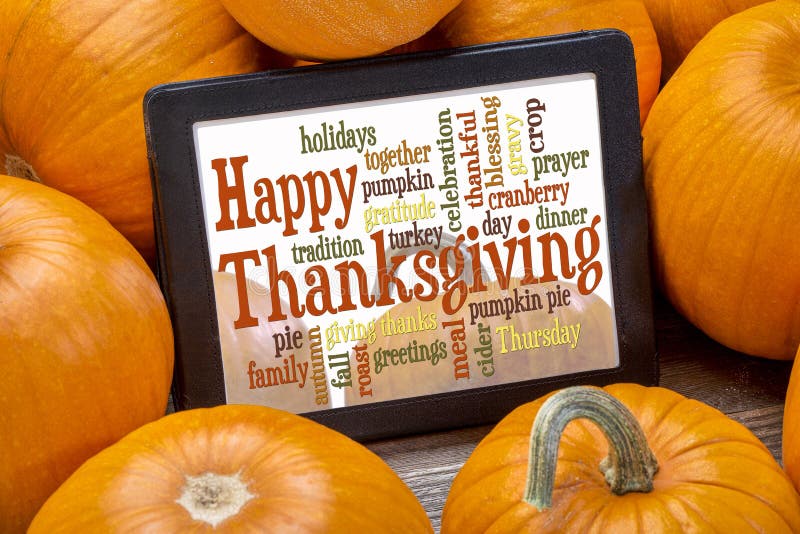 Happy Thanksgiving word cloud on a digital tablet surrounded by pumpkins. Happy Thanksgiving word cloud on a digital tablet surrounded by pumpkins