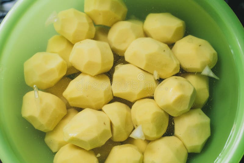 de gepelde aardappels liggen in een groene kom met water kokende eigengemaakte aardappels stock foto's de gepelde aardappels liggen in een groene kom met water kokende eigengemaakte aardappels stock foto's