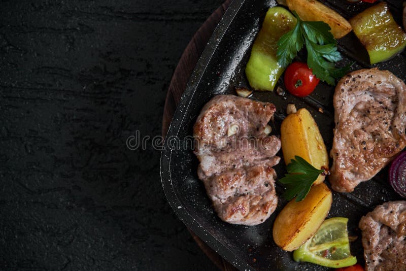De geroosterde filet van varkensvleeslapjes vlees in pan over donkere achtergrond, hoogste mening stock foto De geroosterde filet van varkensvleeslapjes vlees in pan over donkere achtergrond, hoogste mening stock foto