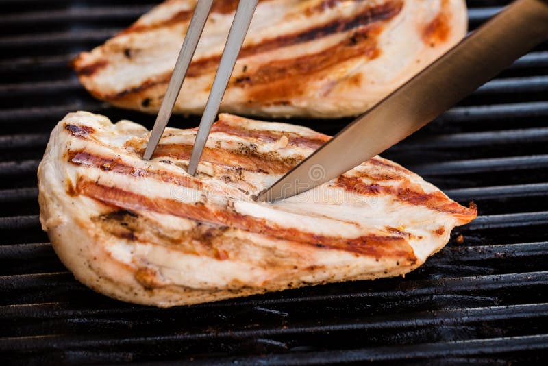 Prepering of grilled chicken breast fillets cutted by knife on BBQ. Prepering of grilled chicken breast fillets cutted by knife on BBQ