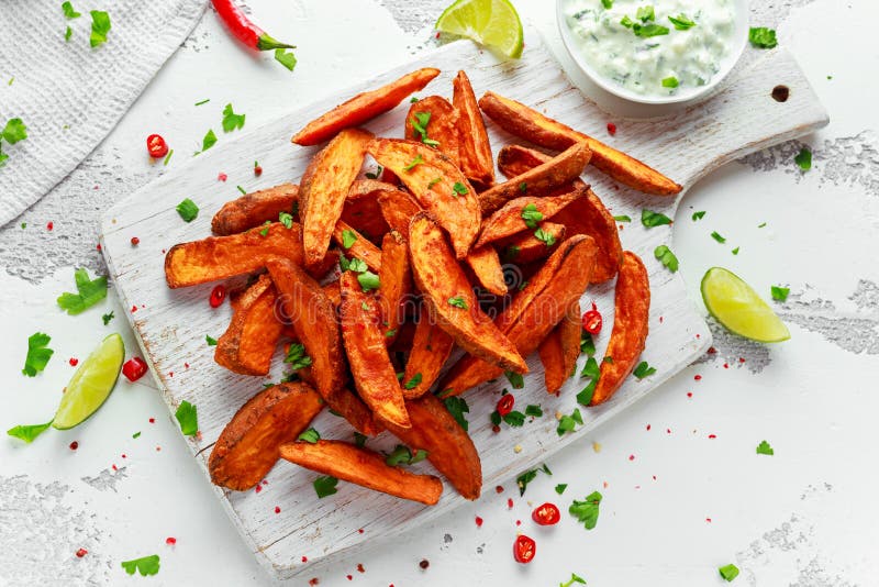 De gezonde Eigengemaakte Gebakken Oranje Bataatwiggen met verse room dompelen saus, kruiden, zout en peper onder stock afbeelding De gezonde Eigengemaakte Gebakken Oranje Bataatwiggen met verse room dompelen saus, kruiden, zout en peper onder stock afbeelding