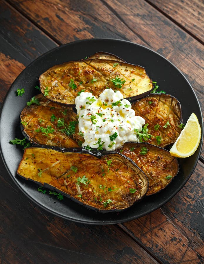 De gezonde vegeterainoven bakte aubergines, Aubergine met kwarkonderdompeling, peterselie en citroenwig stock foto De gezonde vegeterainoven bakte aubergines, Aubergine met kwarkonderdompeling, peterselie en citroenwig stock foto