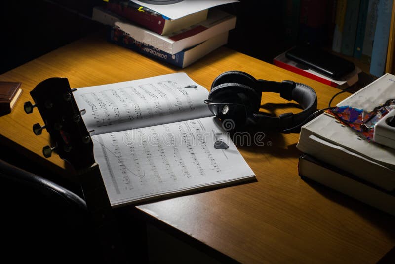 de gitaar en de hoofdtelefoons van het muziekblad op een bureau royalty-vrije stock fotografie de gitaar en de hoofdtelefoons van het muziekblad op een bureau royalty-vrije stock fotografie