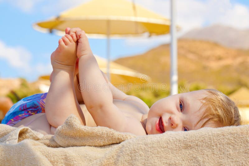 De glimlachende baby die op het strand rusten sunbed stock foto's De glimlachende baby die op het strand rusten sunbed stock foto's