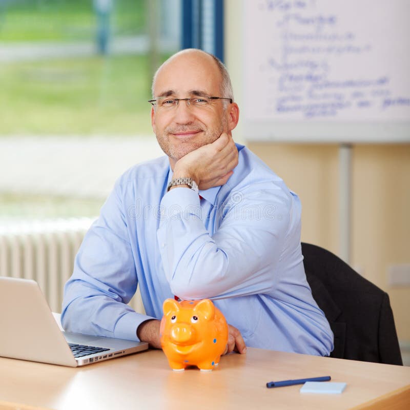 De glimlachende Bank van Zakenmanleaning on piggy stock fotografie De glimlachende Bank van Zakenmanleaning on piggy stock fotografie