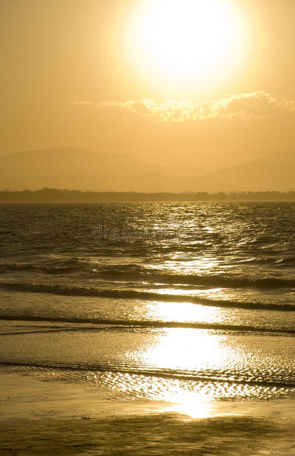 Golden sunset on the beach with dazzling reflections in the ocean surf at Byron Bay on the north coast of New South Wales Australia. Golden sunset on the beach with dazzling reflections in the ocean surf at Byron Bay on the north coast of New South Wales Australia