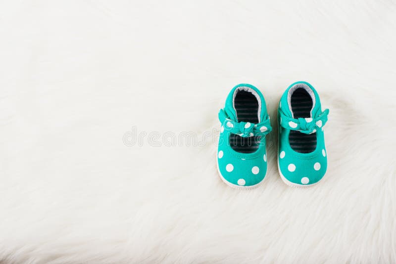 De groene schoenen van het babymeisje met witte punten Op een wit bonttapijt stock foto De groene schoenen van het babymeisje met witte punten Op een wit bonttapijt stock foto