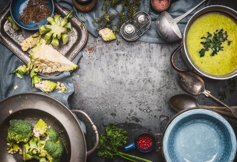 De groene soep van Romanesco en van broccoli met het koken van ingrediënten, keukengereedschap, gietlepel, kommen en lepels op do royalty-vrije stock afbeelding De groene soep van Romanesco en van broccoli met het koken van ingrediënten, keukengereedschap, gietlepel, kommen en lepels op do royalty-vrije stock afbeelding