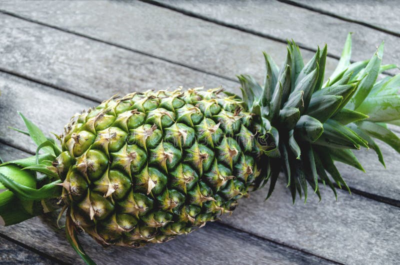 De groene verse Close-up van het ananasfruit op een oude houten achtergrond met aardlicht royalty-vrije stock afbeeldingen De groene verse Close-up van het ananasfruit op een oude houten achtergrond met aardlicht royalty-vrije stock afbeeldingen