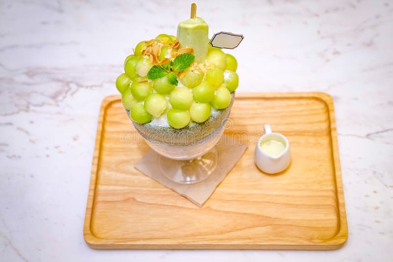 de groene vorm van de meloenbal wordt geschikt op de bovenkant van bingsu (Koreaanse roomijsstijl) en met groene theeroomijs en m royalty-vrije stock foto de groene vorm van de meloenbal wordt geschikt op de bovenkant van bingsu (Koreaanse roomijsstijl) en met groene theeroomijs en m royalty-vrije stock foto