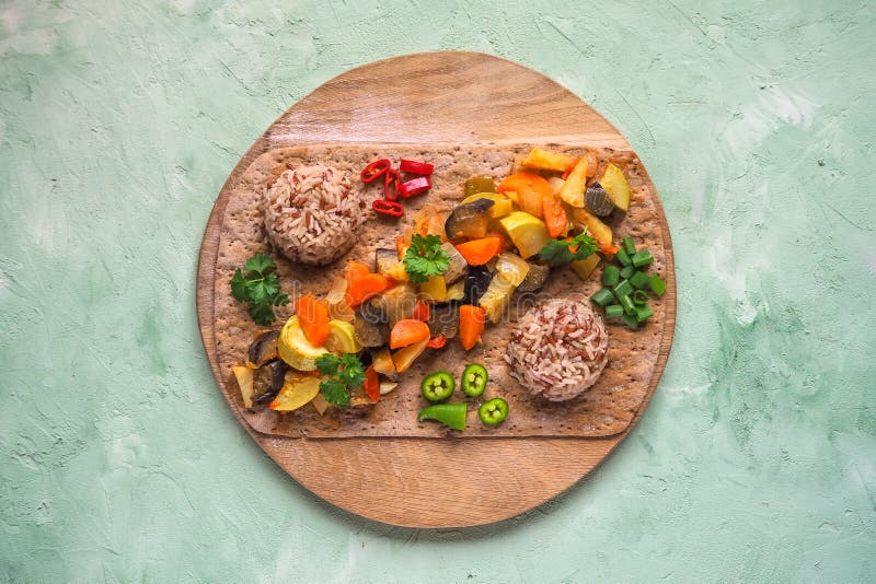 De groente versiert van gestoofde groenten en wilde rijst op een rond hakbord Gezond vegetarisch voedsel stock foto De groente versiert van gestoofde groenten en wilde rijst op een rond hakbord Gezond vegetarisch voedsel stock foto