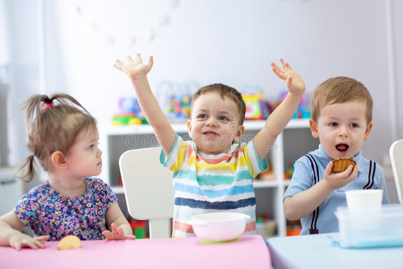 De groep gelukkige jonge geitjes heeft een lunch in kleuterschool royalty-vrije stock afbeeldingen De groep gelukkige jonge geitjes heeft een lunch in kleuterschool royalty-vrije stock afbeeldingen