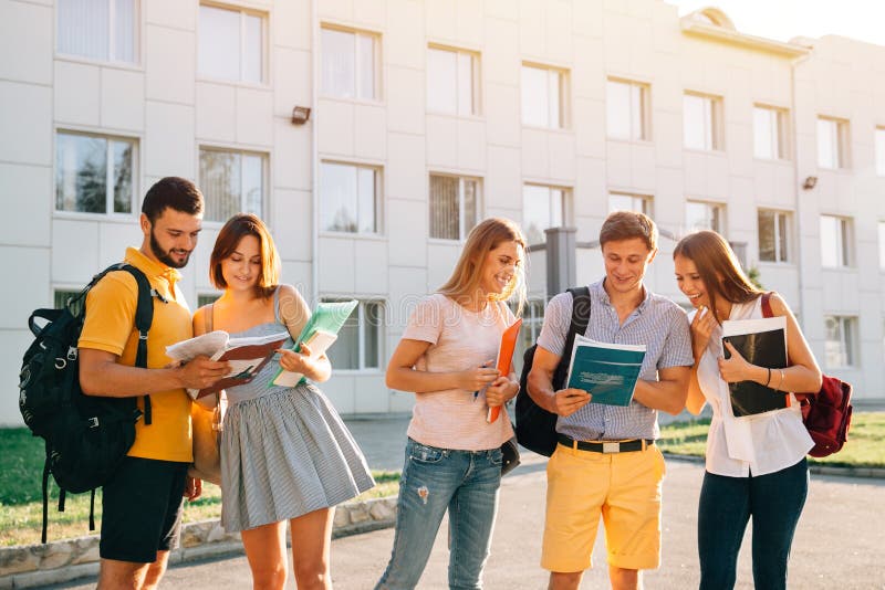 De groep vrolijke studententieners met notaboeken bestudeert in openlucht bij campus Onderwijs en tienerconcept stock afbeelding De groep vrolijke studententieners met notaboeken bestudeert in openlucht bij campus Onderwijs en tienerconcept stock afbeelding