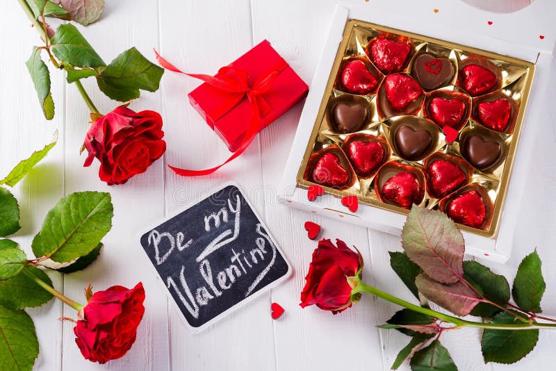 De de groetkaart van de valentijnskaartendag met rode rozen en het hart vormden chocolade op houten achtergrond Hoogste mening royalty-vrije stock afbeelding De de groetkaart van de valentijnskaartendag met rode rozen en het hart vormden chocolade op houten achtergrond Hoogste mening royalty-vrije stock afbeelding