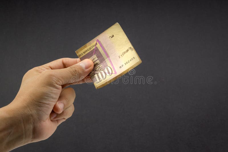 De hand houdt honderd MACEDONIË MUNT, Macedonisch denar Bankbiljet op zwarte achtergrond stock fotografie De hand houdt honderd MACEDONIË MUNT, Macedonisch denar Bankbiljet op zwarte achtergrond stock fotografie