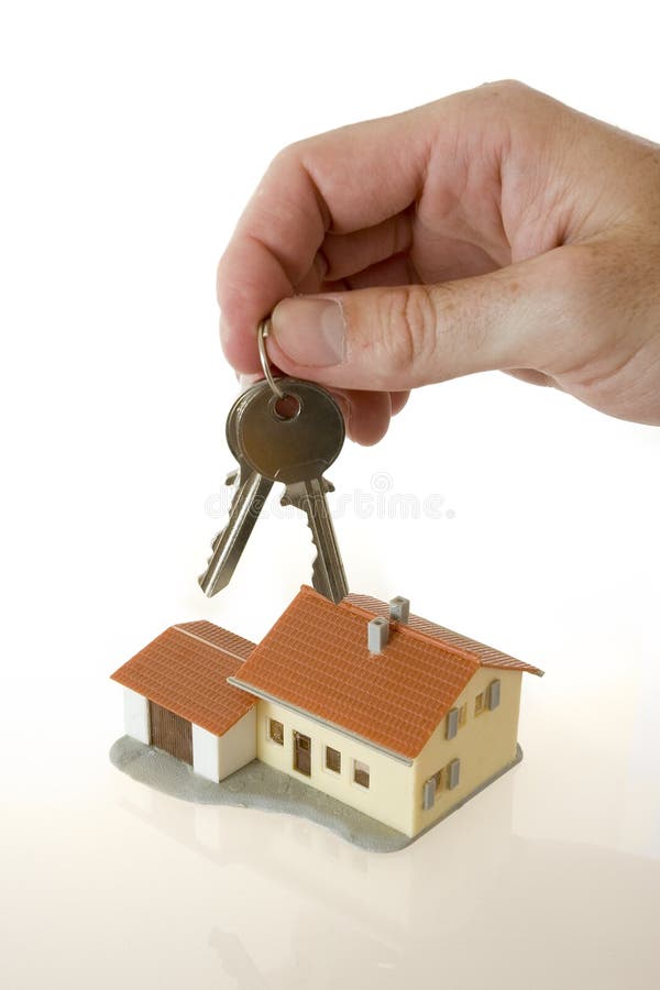 De hand van de zakenman met sleutels en een klein huis