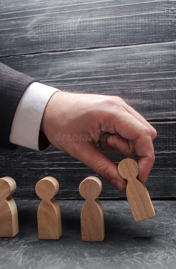 De hand van een zakenman legt een houten cijfer op een rij van een mens aan andere werknemers voor Het concept bedrijfseconomie stock fotografie De hand van een zakenman legt een houten cijfer op een rij van een mens aan andere werknemers voor Het concept bedrijfseconomie stock fotografie