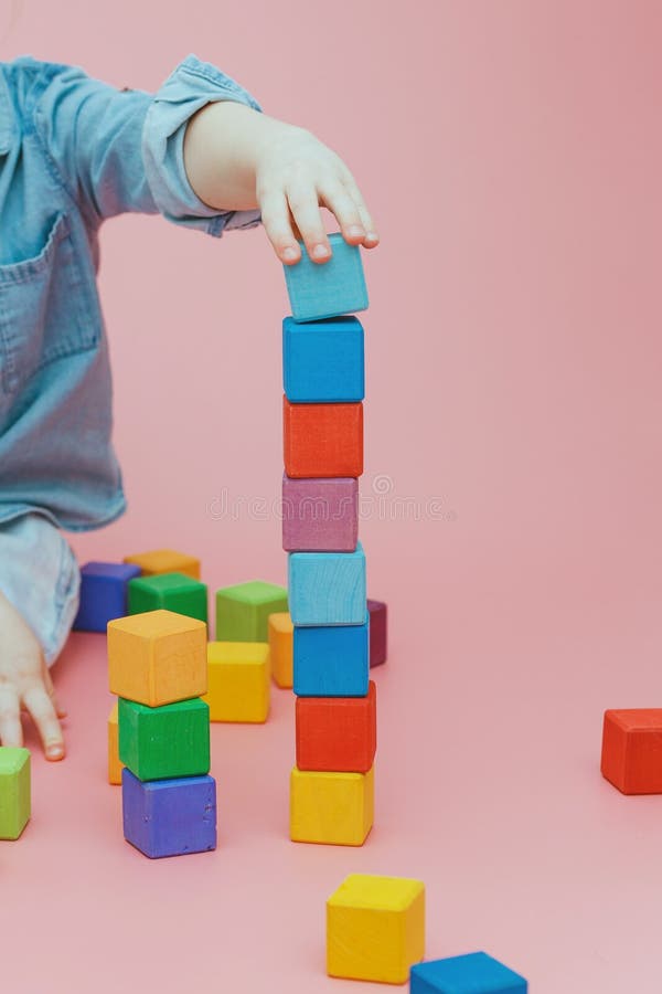 De hand van kinderen bouwt een toren van houten gekleurde kubussen stock foto De hand van kinderen bouwt een toren van houten gekleurde kubussen stock foto