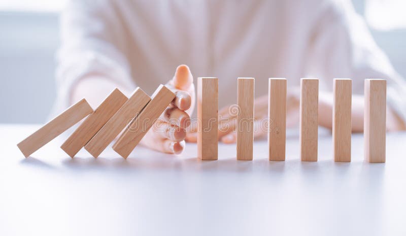 Woman`s Hand stop wooden domino business crisis effect, risk protection concept. Woman`s Hand stop wooden domino business crisis effect, risk protection concept