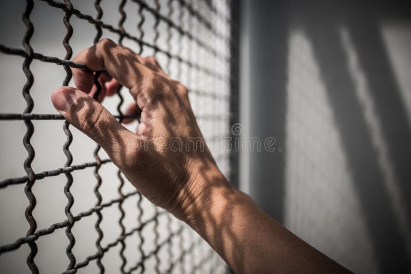 De hand van rustieke het metaalomheining van de gevangeneholding met patroonschaduw, misdadiger sloot in gevangenis stock fotografie De hand van rustieke het metaalomheining van de gevangeneholding met patroonschaduw, misdadiger sloot in gevangenis stock fotografie