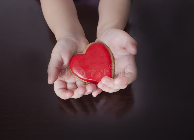 De handen die van het kind het hart op de houten achtergrond houden Het concept het geven, familie, bescherming, liefde, gezondhe stock fotografie De handen die van het kind het hart op de houten achtergrond houden Het concept het geven, familie, bescherming, liefde, gezondhe stock fotografie