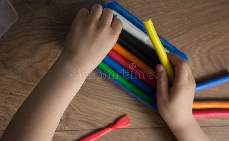 De handen van het meisje nemen de multi-colored klei royalty-vrije stock afbeelding De handen van het meisje nemen de multi-colored klei royalty-vrije stock afbeelding