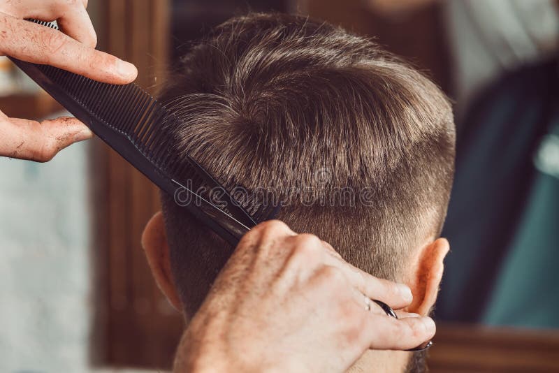 De handen van jonge kapper die tot kapsel maken aan de aantrekkelijke mens in herenkapper royalty-vrije stock afbeelding De handen van jonge kapper die tot kapsel maken aan de aantrekkelijke mens in herenkapper royalty-vrije stock afbeelding