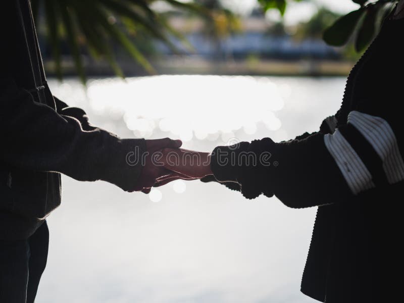 De handen van de paarholding naast de meer vage achtergrond De liefde & gaat samen Concept stock fotografie De handen van de paarholding naast de meer vage achtergrond De liefde & gaat samen Concept stock fotografie
