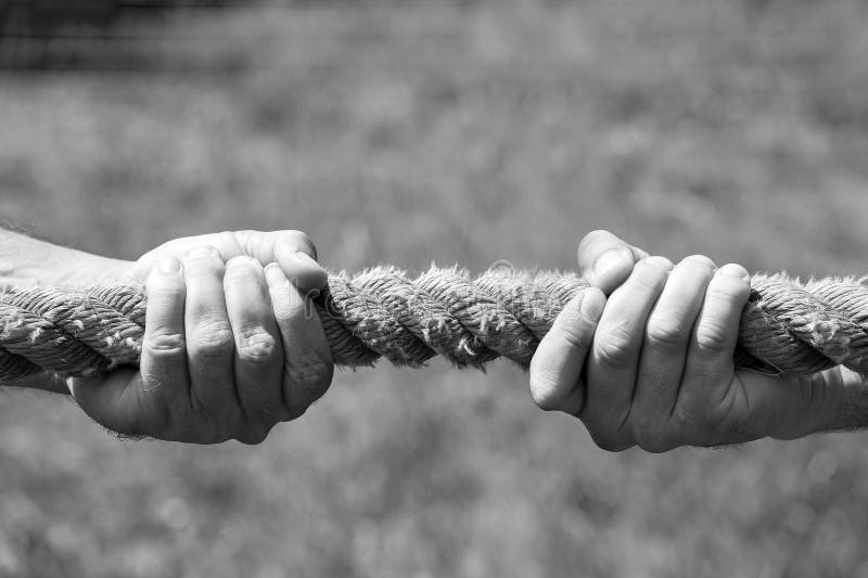 De handen van twee mensen trekken de kabel elk in zijn eigen richting Het concept geschil, conflict en kracht Rebecca 36 royalty-vrije stock foto De handen van twee mensen trekken de kabel elk in zijn eigen richting Het concept geschil, conflict en kracht Rebecca 36 royalty-vrije stock foto