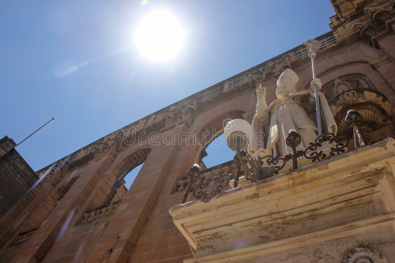 De heilige op de voorgevel van de kerk van St Publius ` richt aan de zon met zijn vinger stock fotografie De heilige op de voorgevel van de kerk van St Publius ` richt aan de zon met zijn vinger stock fotografie