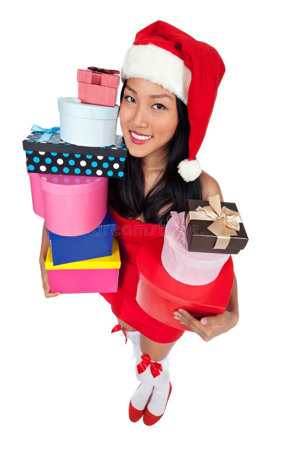 A wide angle shot an Asian girl in a red dress wearing an Xmas hat while holding gifts. A wide angle shot an Asian girl in a red dress wearing an Xmas hat while holding gifts.