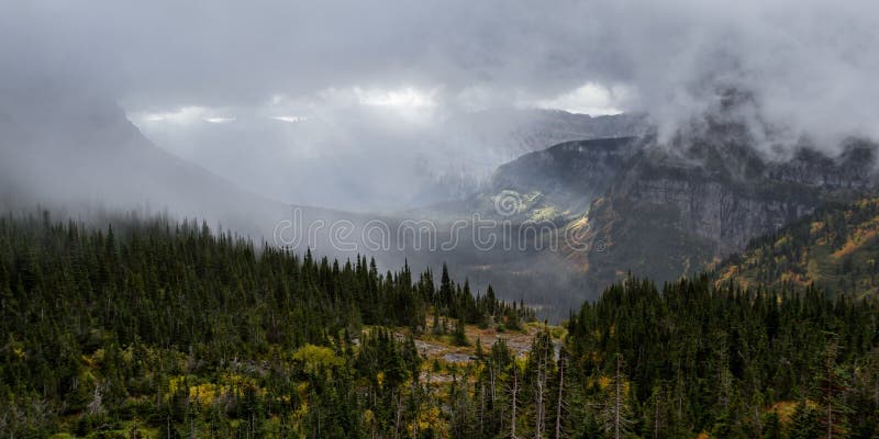 Serene landscape in Glacier NP Montana with a dense fog clinging to the mountains and warm sunshine rays breaking thru sections of the valley and peaks. Serene landscape in Glacier NP Montana with a dense fog clinging to the mountains and warm sunshine rays breaking thru sections of the valley and peaks