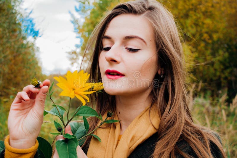 De herfstportret, jong mooi meisje met lang haar in aard met heldere gele bloem stock afbeelding De herfstportret, jong mooi meisje met lang haar in aard met heldere gele bloem stock afbeelding