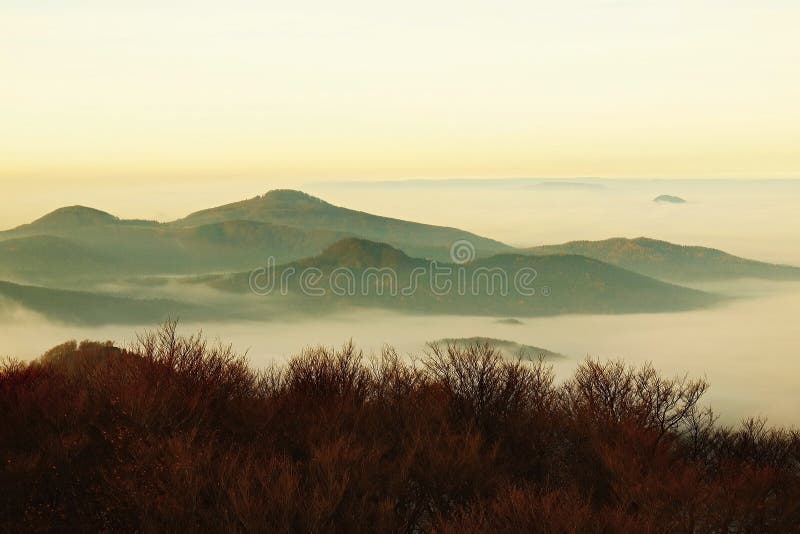 De herfstzonsopgang in een mooie berg van Bohemen. Pieken van heuvels die van mist worden verhoogd.
