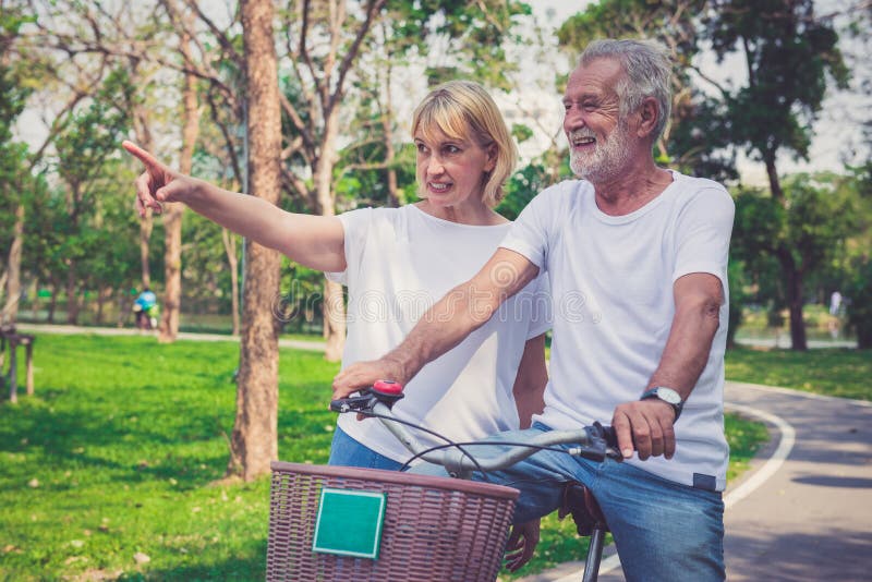 De hogere Berijdende Fietsen van het Paar in Park royalty-vrije stock afbeelding De hogere Berijdende Fietsen van het Paar in Park royalty-vrije stock afbeelding
