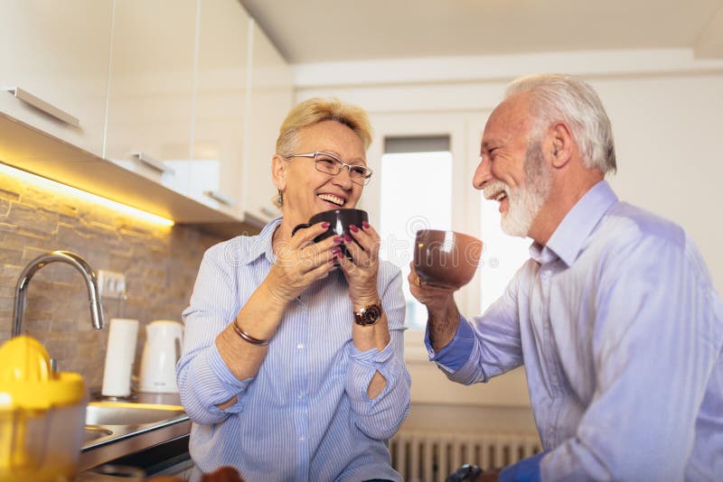 De hogere man en de vrouw koppelen zitting die samen thuis en thee of koffie glimlachen drinken stock afbeelding De hogere man en de vrouw koppelen zitting die samen thuis en thee of koffie glimlachen drinken stock afbeelding