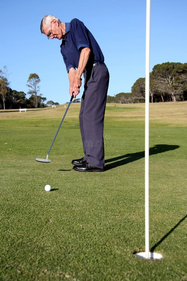 Senior golfer putting on a golf green. Senior golfer putting on a golf green