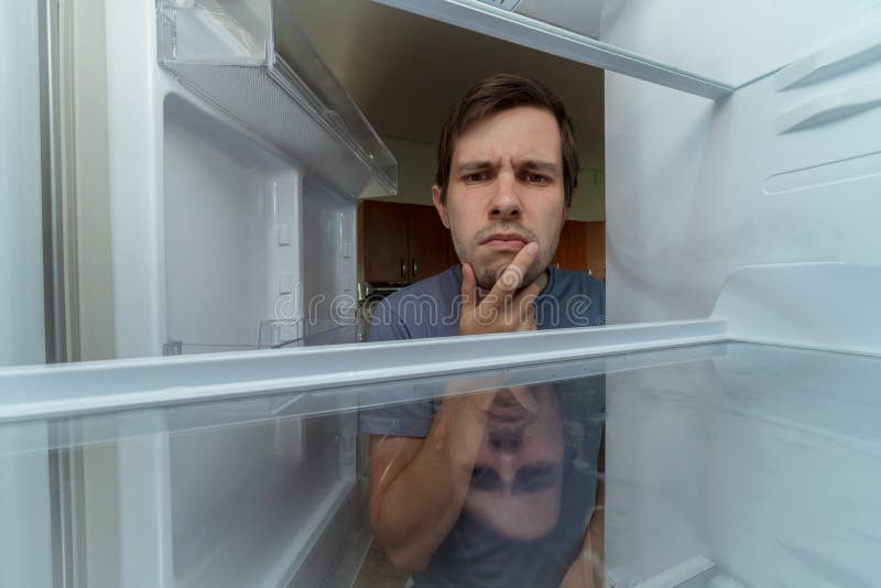 De hongerige mens zoekt voedsel in lege koelkast