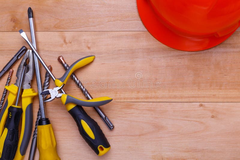 De hulpmiddelen liggen in een hoop in de linkerhoek naast de helm op een houten achtergrond Mening van hierboven stock fotografie De hulpmiddelen liggen in een hoop in de linkerhoek naast de helm op een houten achtergrond Mening van hierboven stock fotografie