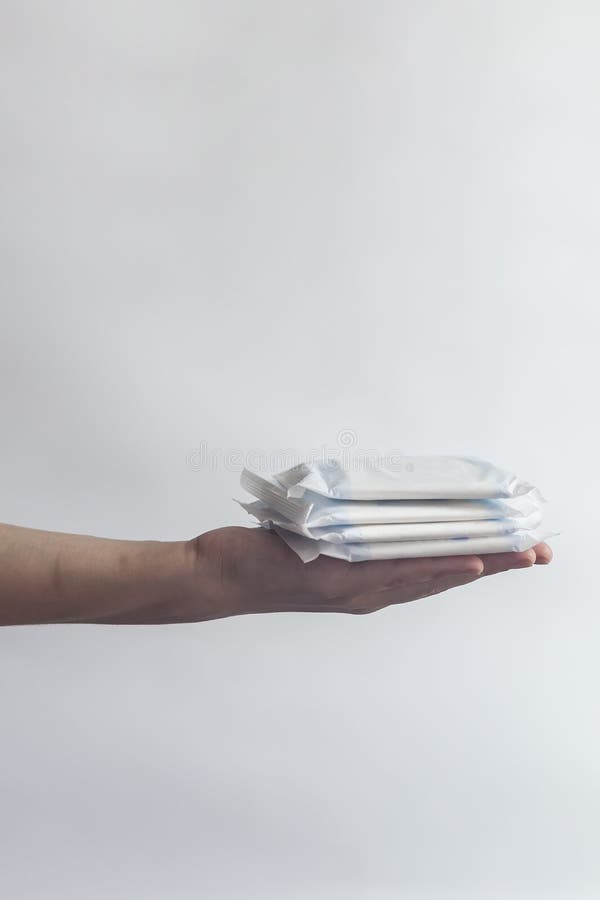De hygi?neproducten van het wijfje De hand die van de vrouw een stapel maandverbanden houden tegen witte achtergrond Het concept stock afbeeldingen De hygi?neproducten van het wijfje De hand die van de vrouw een stapel maandverbanden houden tegen witte achtergrond Het concept stock afbeeldingen
