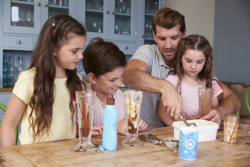 De Ijscoupes van vadermaking ice cream met Kinderen thuis stock foto De Ijscoupes van vadermaking ice cream met Kinderen thuis stock foto