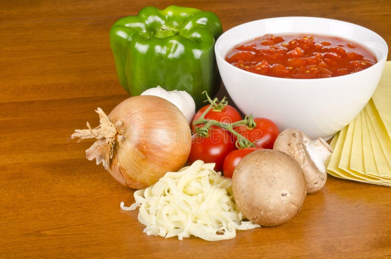 Crushed tomatoes in a white bowl surrounded with fresh vegetables, fresh pasta and shredded Mozzarella cheese. Crushed tomatoes in a white bowl surrounded with fresh vegetables, fresh pasta and shredded Mozzarella cheese.