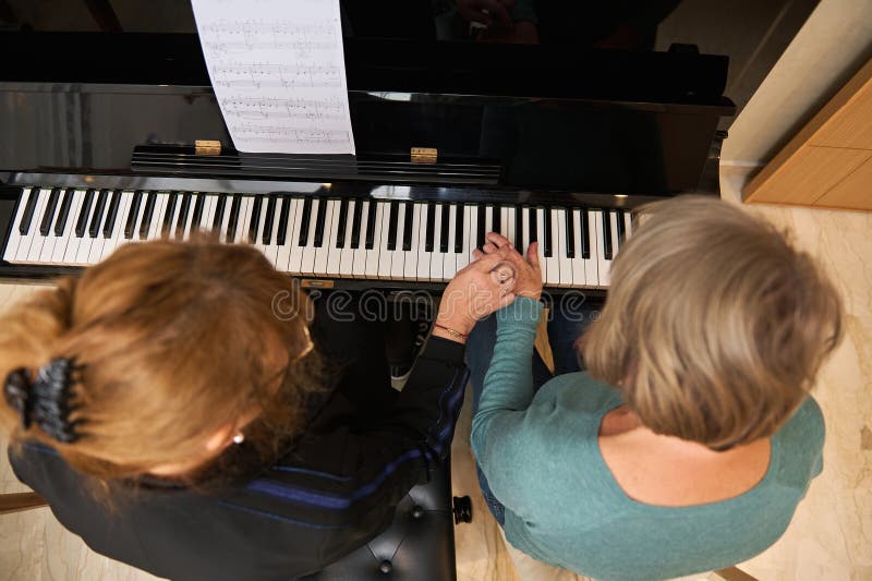 De jolies musiciennes captivées dans une leçon de studio de musique harmonisant les mélodies sur piano acoustique tout en chantant photos stock