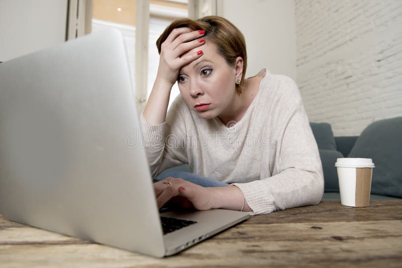 De jonge aantrekkelijke en bezige laag die van de vrouwen thuis bank wat laptop computerwerk in spanning doen kijken die die in o