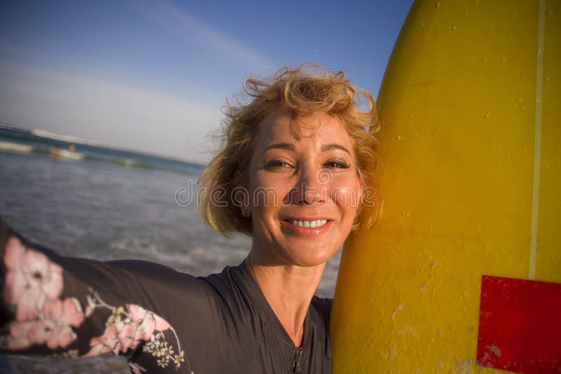 De jonge aantrekkelijke en gelukkige vrouw van de blondesurfer in de brandingsraad van de zwempakholding in het strand die zelfpo stock afbeelding De jonge aantrekkelijke en gelukkige vrouw van de blondesurfer in de brandingsraad van de zwempakholding in het strand die zelfpo stock afbeelding