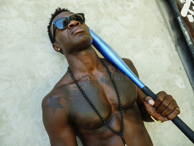 De jonge aantrekkelijke en knappe zwarte afro Amerikaanse mens met geschikt spierlichaam en van de zes pakholding honkbal slaat k royalty-vrije stock afbeeldingen De jonge aantrekkelijke en knappe zwarte afro Amerikaanse mens met geschikt spierlichaam en van de zes pakholding honkbal slaat k royalty-vrije stock afbeeldingen